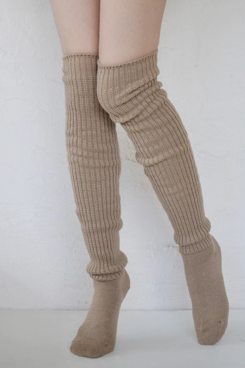 Front view of a woman's leg wearing a pair of TABBISOCKS brand Scrunchy Over the Knee Socks, knee-length knee socks in Milk Tea color
