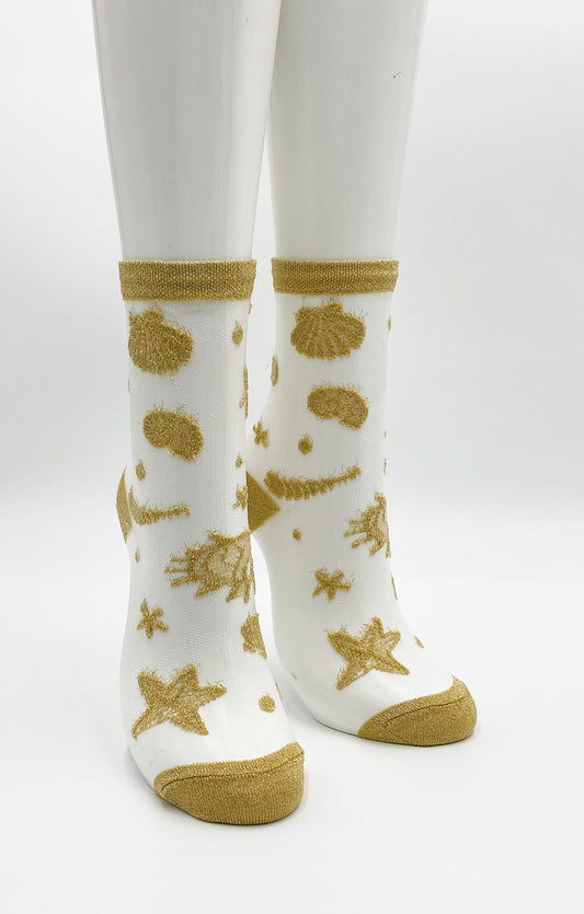 TABBISOCKS brand Shimmery Clear Seashell Socks in CLEAR GOLD color with gold-colored seashell and starfish embroidery scattered on transparent white fabric.