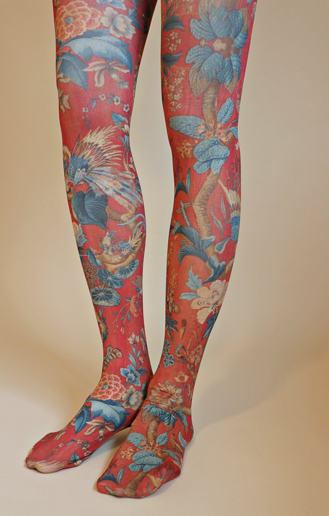 Overall reddish fabric with large light blue and ivory colored floral patterns throughout the tights.