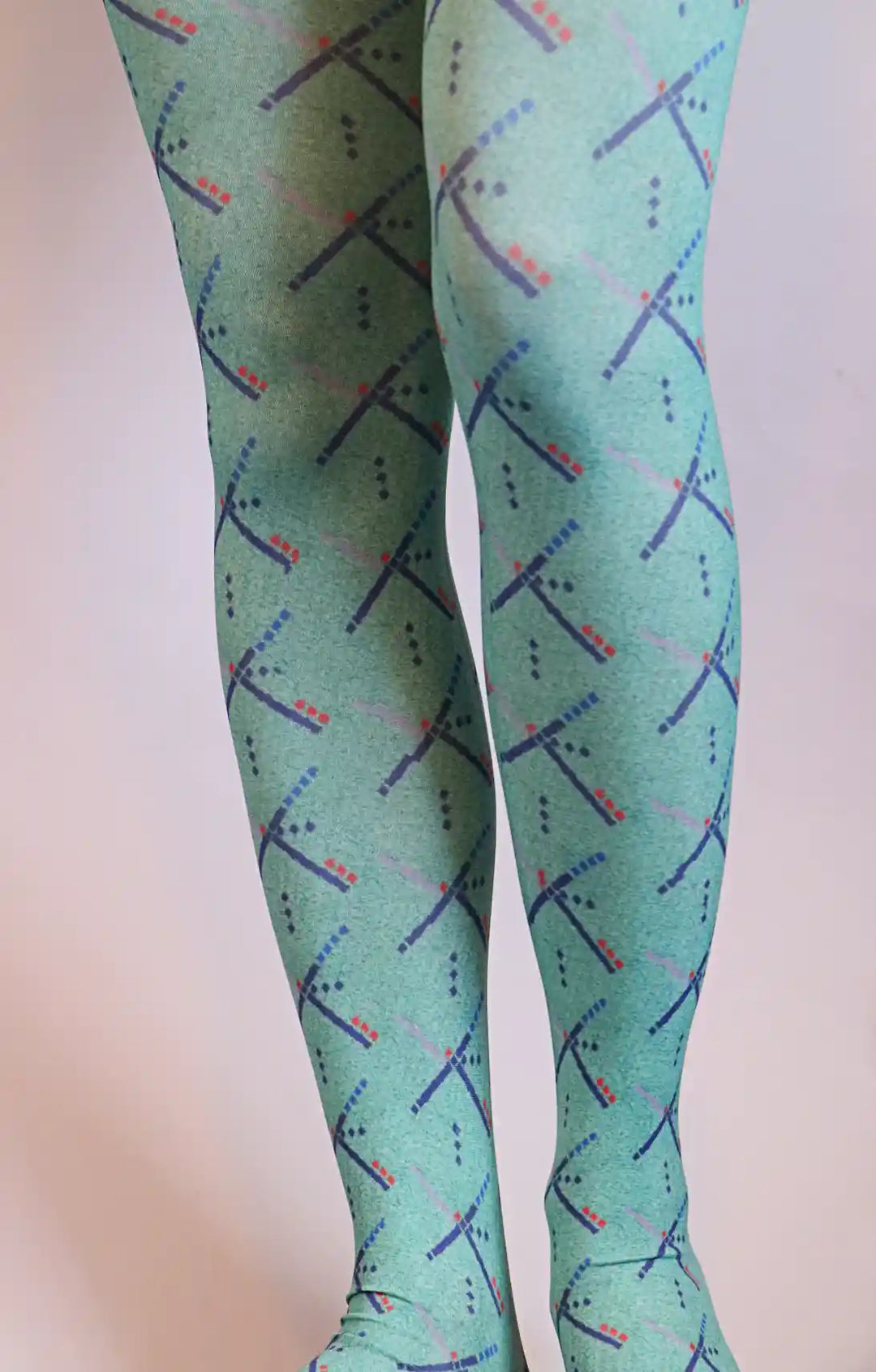 Female leg wearing TABBISOCKS brand PDX Carpet Patterned Tights, emerald green in color with an overall PDX Carpet pattern