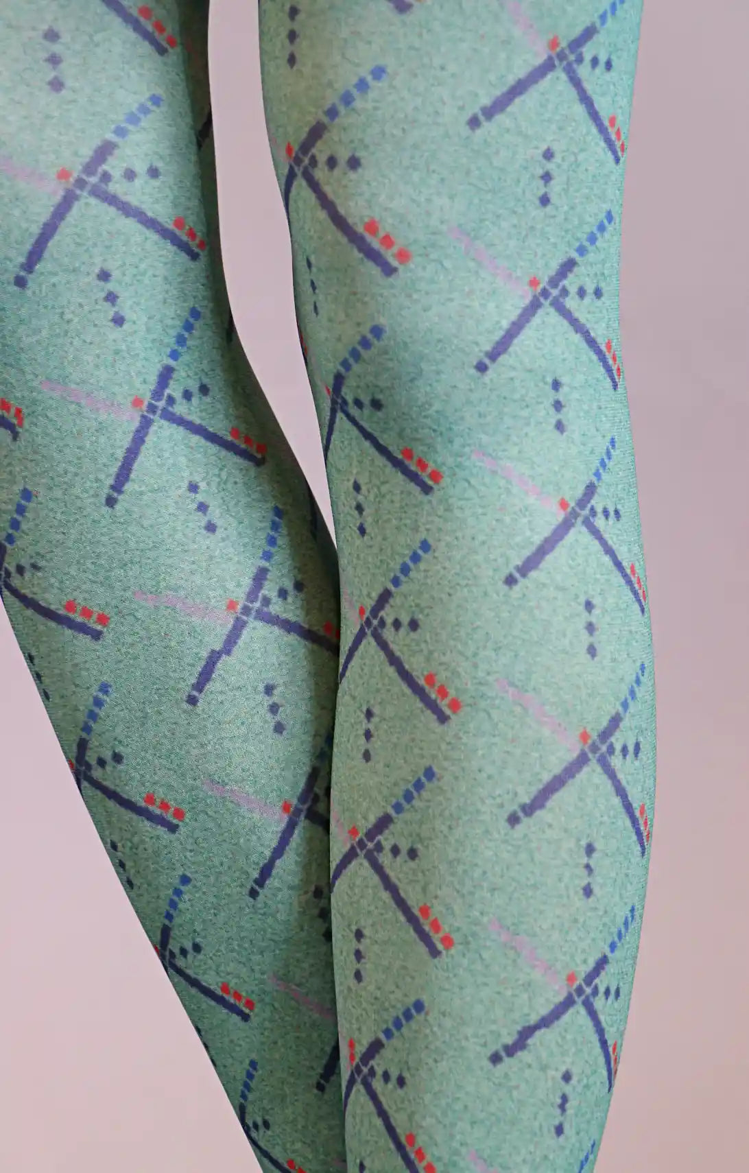 TABBISOCKS brand PDX Carpet Patterned Tights, enlarged view of the knee area of a woman's leg wearing tights that are emerald green in color with an overall PDX Carpet pattern