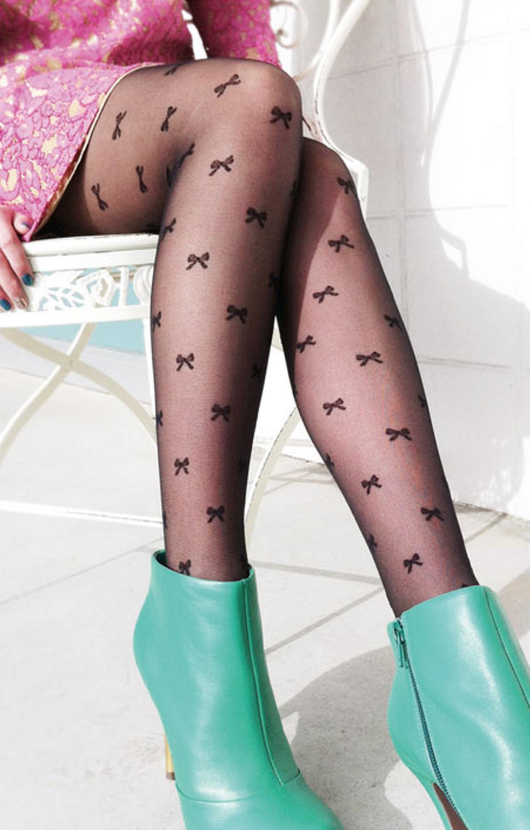 Woman wearing TABBISOCKS brand Ribbon Sheer Tights black pantyhose with black ribbon embroidery throughout, pink dress and emerald green leather short boots