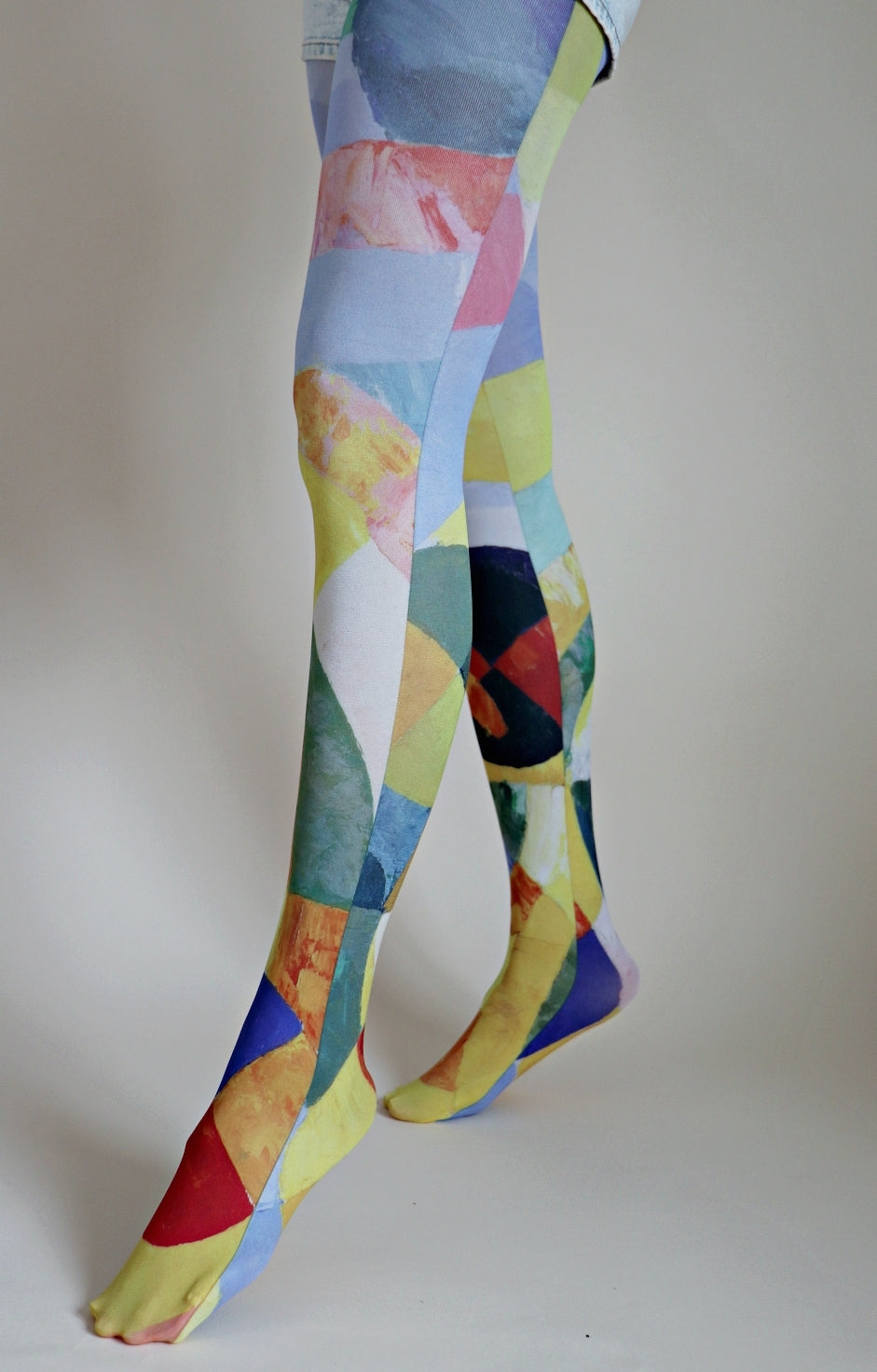 Tights inspired by the work Circular Forms by Robert Delaunay of the TABBISOCKS brand, with the colors light blue, red, blue, green, pink and other geometric patterns on the legs of a woman wearing