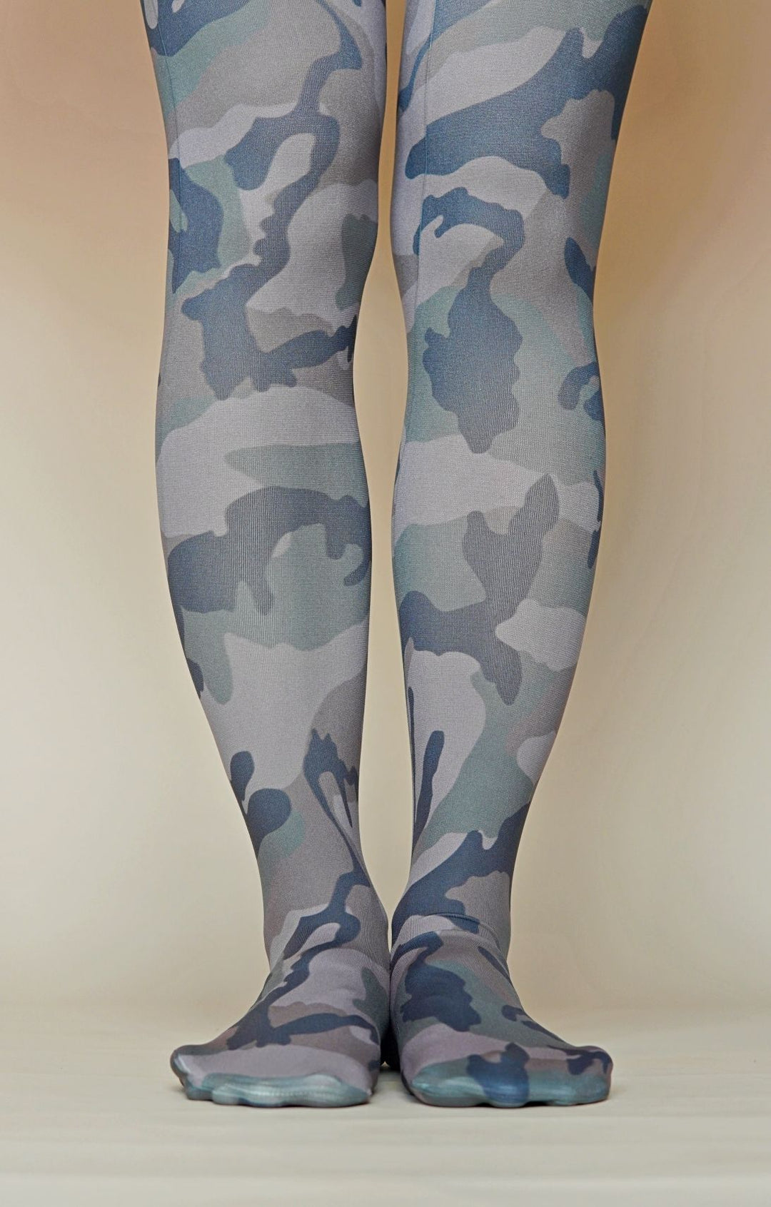 A pair of camouflage printed tights worn on a model, with the pattern visible on the legs and feet.