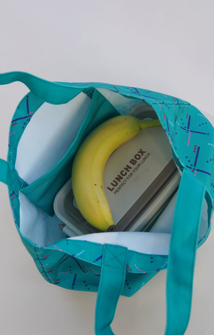 Teal tote bag with a lunch box and banana on a white background