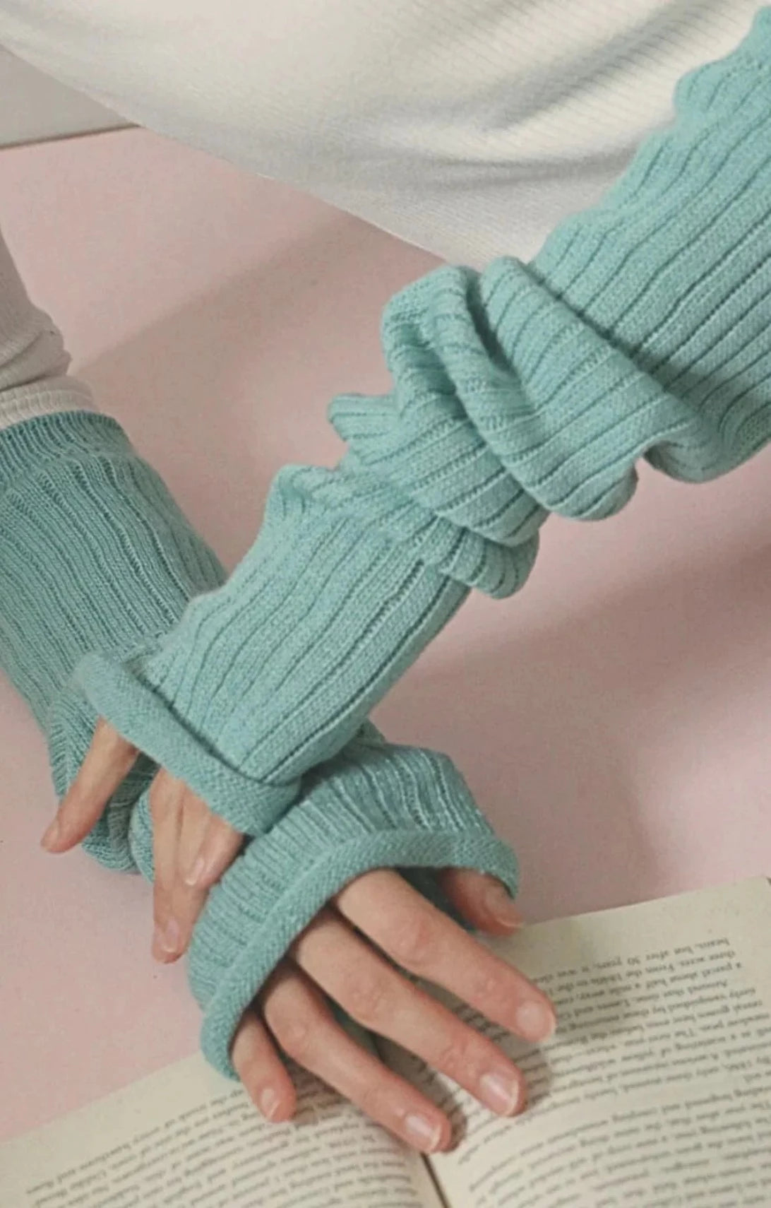 Arm of a woman reading a book wearing an ivory-colored cut sleeve wearing TABBISOCKS brand Wool Blend Arm Warmers Dusty Mint