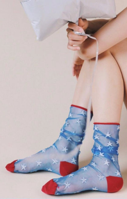 Sitting leg of a woman wearing a pair of socks in BLUE SILVER STAR color with red point color of a product called American Star Tulle Sheer Socks of TABBISOCKS brand