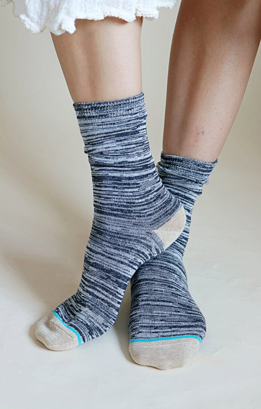 A woman's leg wearing a pair of TABBISOCKS brand Heather Organic Cotton socks with CHARCOAL colored stripes, cream toes and heels, and light blue lines as the point color