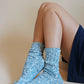 Leg of a woman sitting in a navy blue mini skirt wearing TABBISOCKS brand Organic Cotton Slub Crew Socks in Teal color