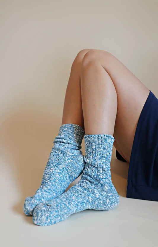 Leg of a woman sitting in a navy blue mini skirt wearing TABBISOCKS brand Organic Cotton Slub Crew Socks in Teal color